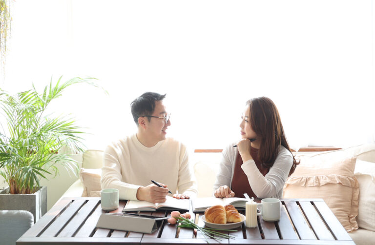 beautiful young couple having a conversation while looking at each other over a window background in a bright room